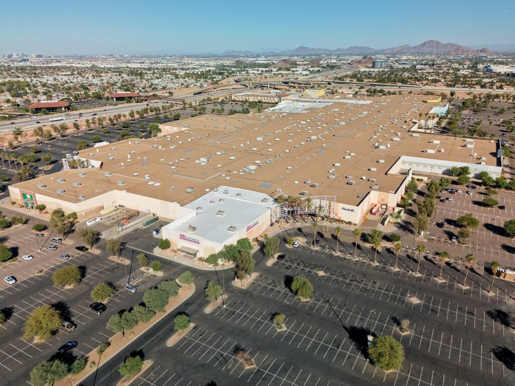Aerial view of the Arizona Mills outlet mall's large flat roof and surrounding parking lots in Tempe, with the city and mountains beyond