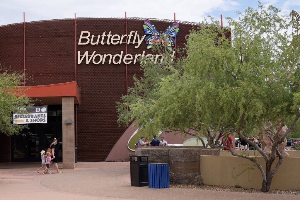 Families walking toward the Butterfly Wonderland entrance at the Arizona Boardwalk in Scottsdale, with its big butterfly sign above