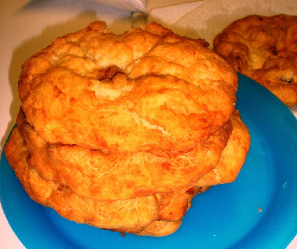 A stack of golden, puffy fry bread rounds on a blue plate
