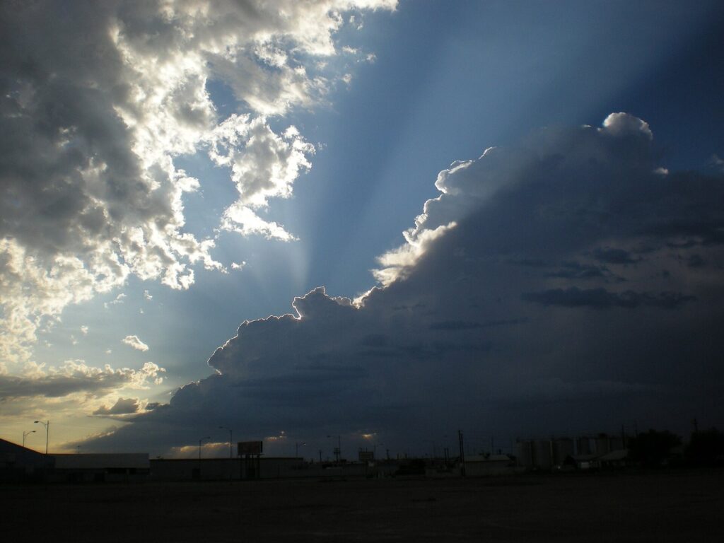 Dark clouds with sunbeams breaking through over low buildings on Grand Avenue in Phoenix