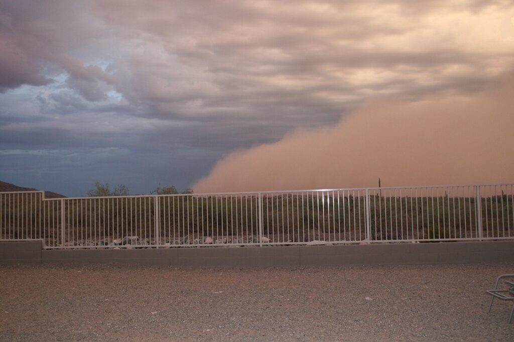 A towering wall of dust rolling toward an Ahwatukee neighborhood under dark storm clouds, the monsoon hazard any Phoenix travel guide should cover