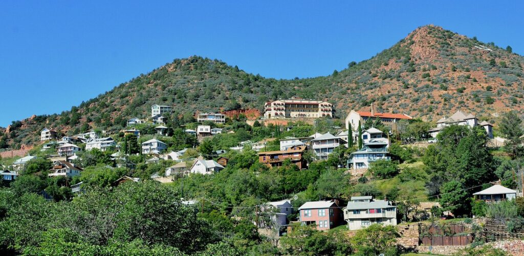 Houses and old commercial buildings stacked up a green hillside in Jerome, Arizona, one of the best small-town day trips from Phoenix
