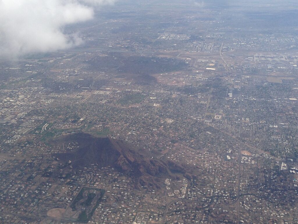 Camelback Mountain rising among Phoenix neighborhoods and Paradise Valley estates, seen from a plane