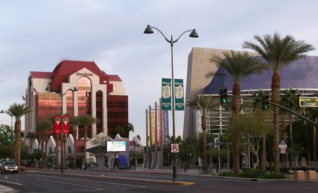 Palm-lined Main Street in downtown Mesa with the Mesa Arts Center and a red-roofed bank tower