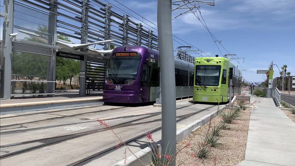 A purple Valley Metro light rail train and a green Tempe Streetcar side by side at a station