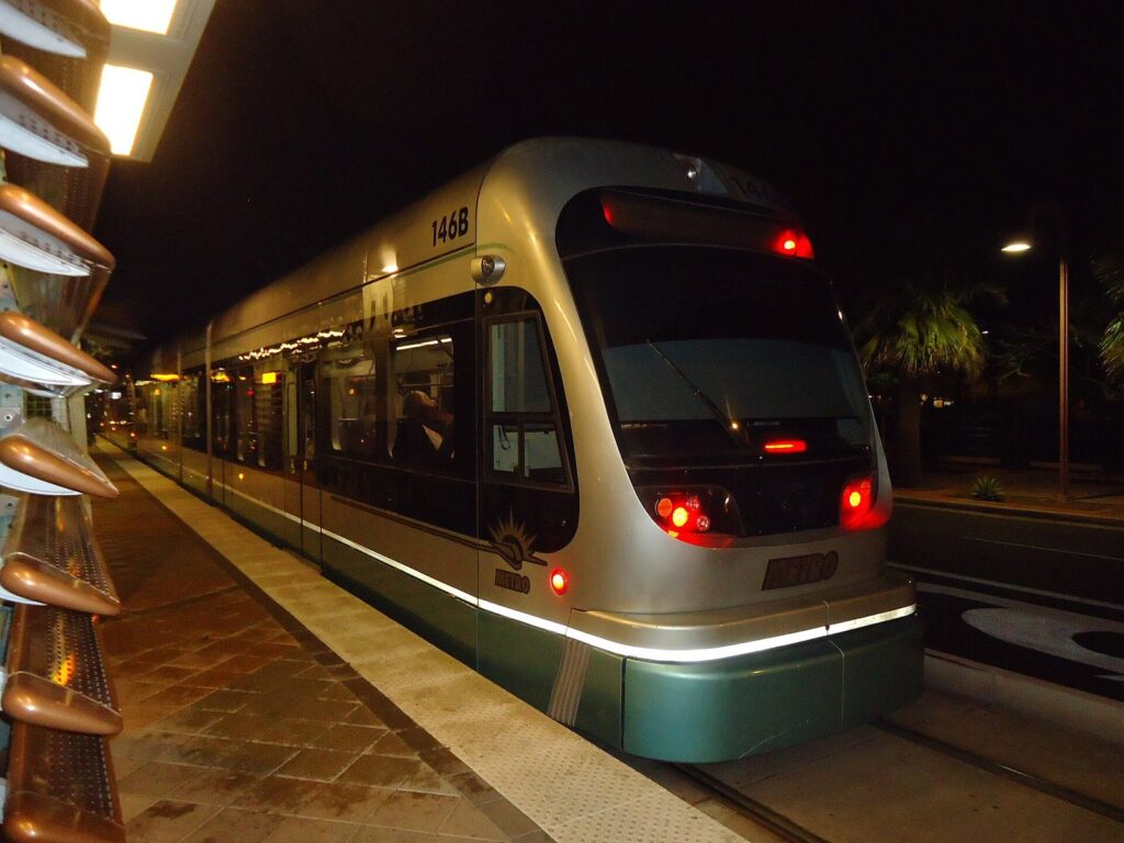 A silver Valley Metro light rail train stopped at a station platform at night